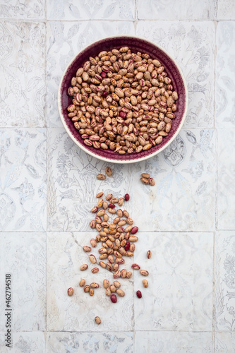 Bowl of dried pinto and borlotto beans lying on tiled surface photo