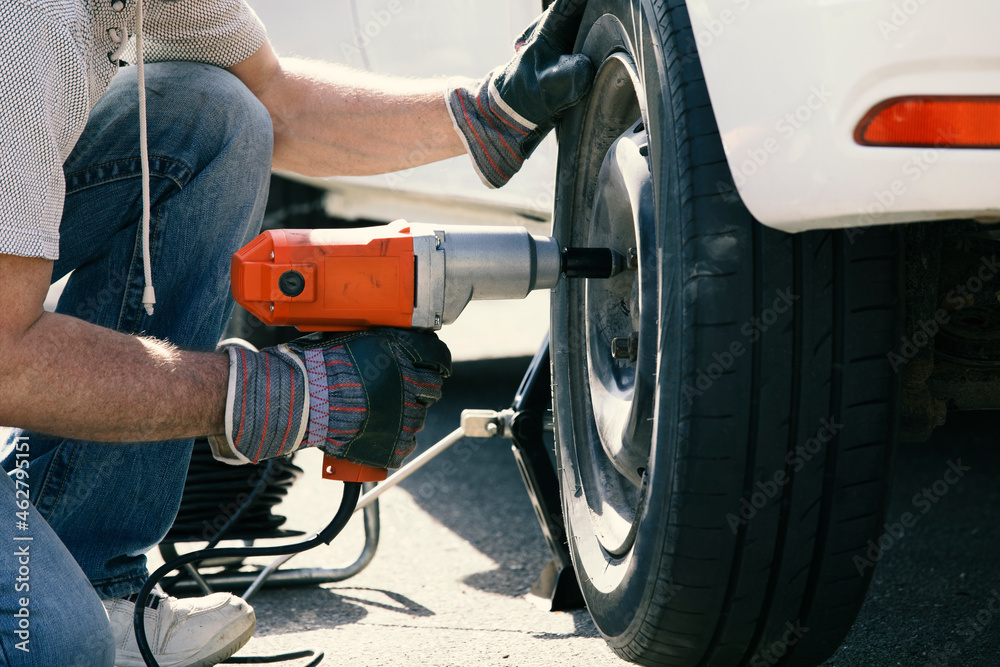 Man changing car tire, partial view Man changing car tire, partial view