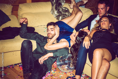 Tired male and female friends resting on sofa in party photo