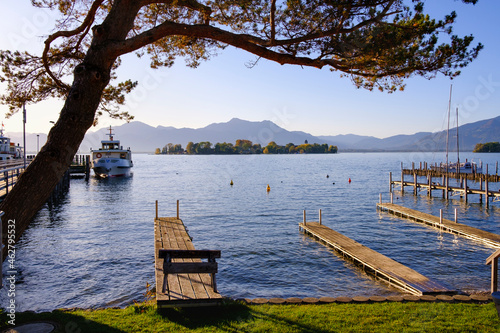 Germany, Bavaria, Gstadt am Chiemsee, Jetties on shore of Chiemsee lake with Fraueninsel in background photo