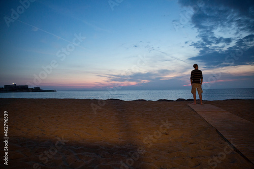 Italy, Sicily, Isola delle Correnti, Lido Scialai, man standing at the beach at dusk photo