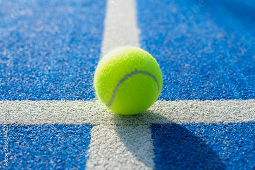 Yellow tennis ball in the court on blue grass - Paddle tennis ball on the court on blue turf © damianobuffo
