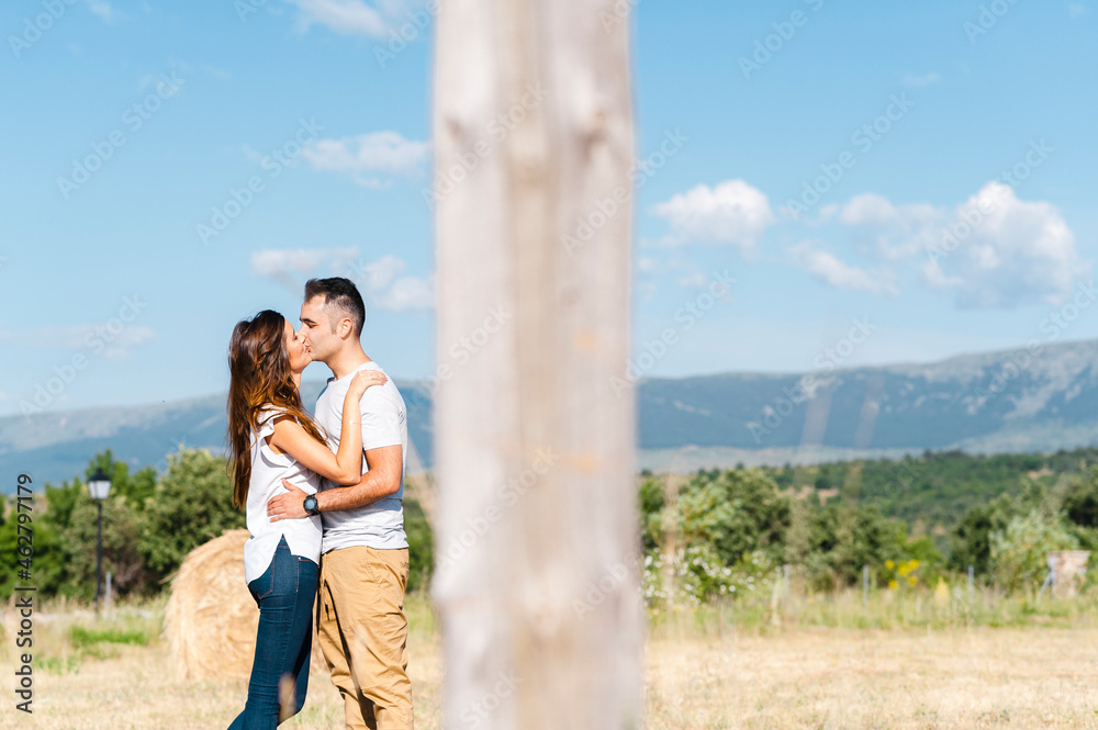 Young couple kissing on agricultural field during sunny day Young couple kissing on agricultural field during sunny day