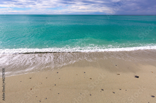 Picturesque view of the turquoise sea and sandy empty beach  foamy water