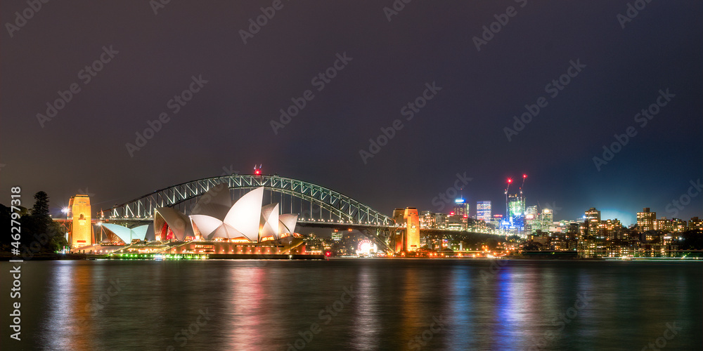 Illuminated Sydney Harbor Bridge and buildings over river against sky at night, Australia Illuminated Sydney Harbor Bridge and buildings over river against sky at night, Australia