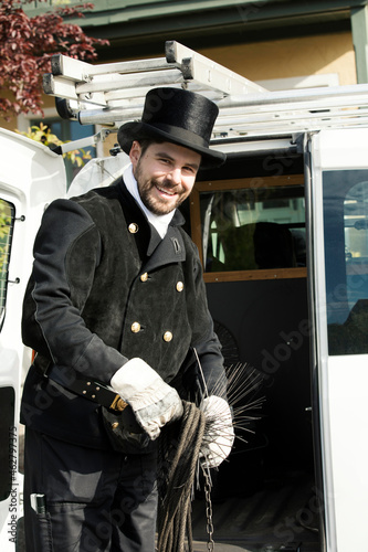 Portrait of smiling chimney sweep at his van