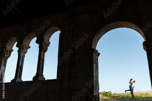 Young man lifting girlfriend seen through arch of Roman church photo