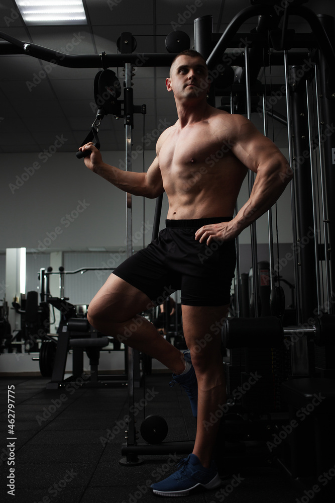 Portrait of a beautiful male athlete bodybuilder in gym, low key, darkness. Posing, coach. press Portrait of a beautiful male athlete bodybuilder in gym, low key, darkness. Posing, coach. press