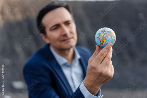 Mature businessman holding a globe on a disused mine tip photo