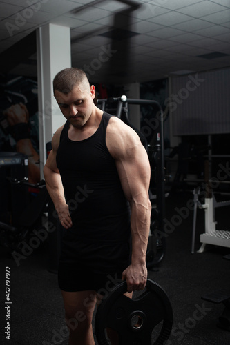 Portrait of a handsome man in gym. Coach, athlete, bodybuilder, muscular sexy body, darkness.