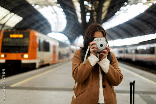 Young woman taking picture with camera at the train station photo