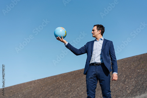 Mature businessman holding a globe on a disused mine tip photo