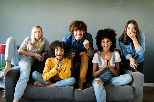 Nervous friends sitting on couch watching tv photo