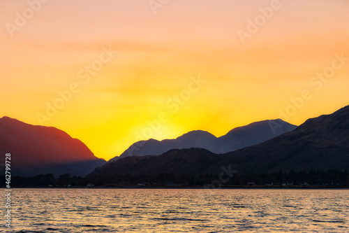 Scenic view of Loch Linnhe with silhouette mountains in background against yellow sky during Sunset, Scotland, UK