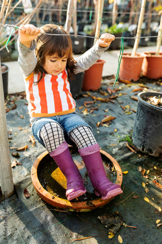 Little girl wearing Wellington Boots playing at pant nursery