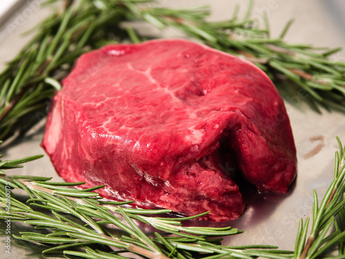 One fillet steak on a metal tray and fresh rosemary herb. Butcher craft product. Finest cut of beef. Meat industry.
