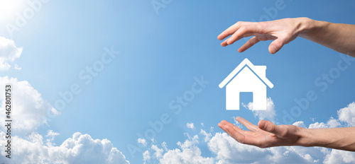 Male hand holding house icon on blue background. Property insurance and security concept.Real estate concept.Banner with copy space.