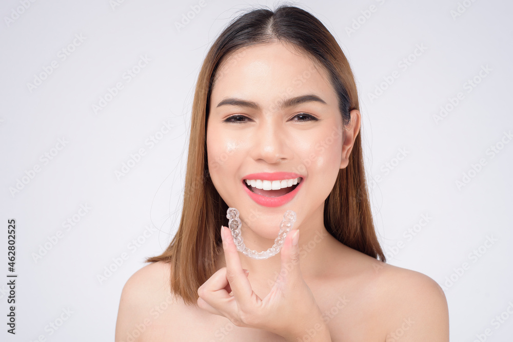 Young smiling woman holding invisalign braces in studio, dental healthcare and Orthodontic concept Young smiling woman holding invisalign braces in studio, dental healthcare and Orthodontic concept