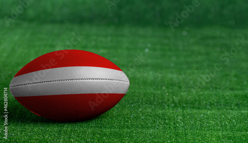 American football ball with Austria flag on green grass background, close up