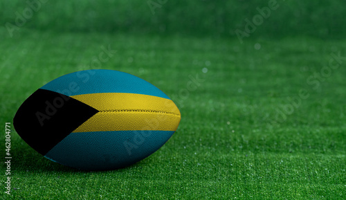 American football ball  with Bahamas flag on green grass background  close up
