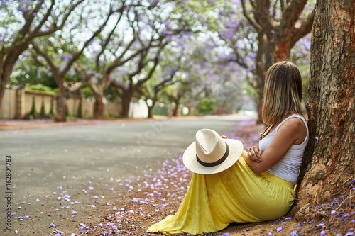 Woman leaning on a tree at a street with jacaranda trees in bloom, Pretoria, South Africa photo