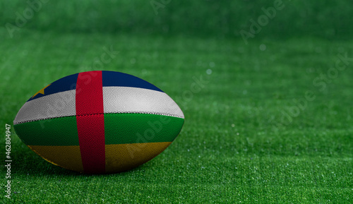 American football ball  with Central African Republic flag on green grass background  close up