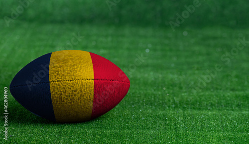 American football ball  with Chad flag on green grass background  close up