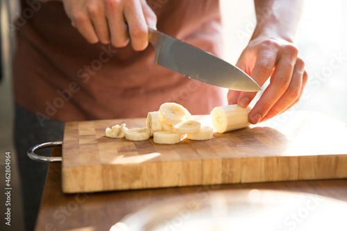 Man's hand chopping banana with kitchen knife