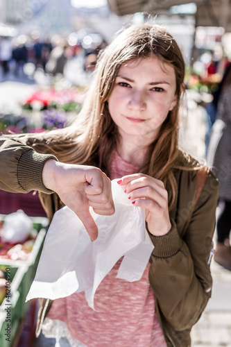 Girl with plastic bag showing thumb down photo