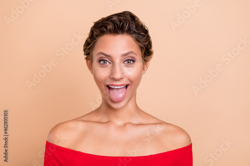 Photo of positive funky cheerful lady stick out tongue make silly face reaction isolated on pastel beige color background