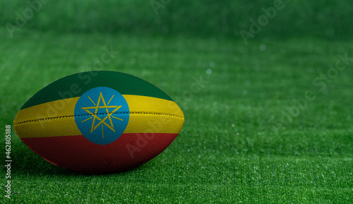American football ball  with Ethiopia flag on green grass background  close up