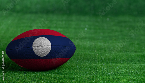 American football ball  with Laos flag on green grass background  close up