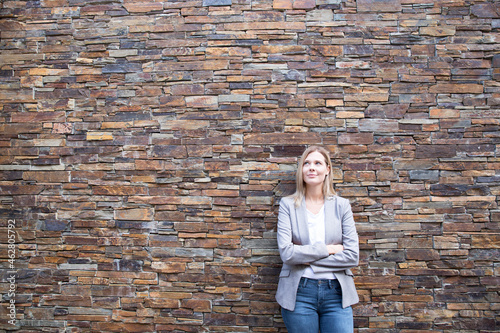 Woman in front of a wall looking upa, arms crossed photo