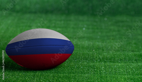 American football ball with Russia flag on green grass background, close up