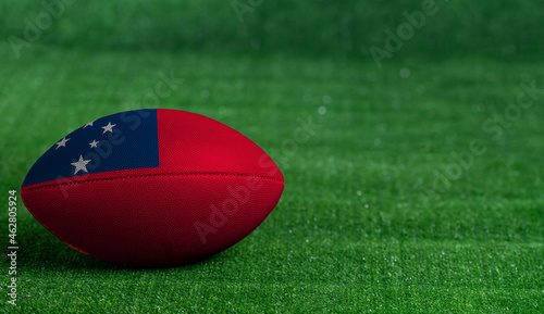 American football ball  with Samoa flag on green grass background  close up