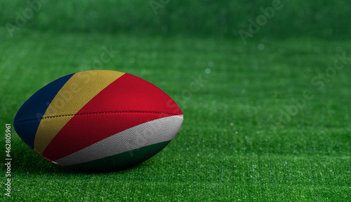 American football ball with Seychelles flag on green grass background, close up