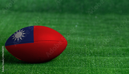 American football ball with Taiwan flag on green grass background, close up