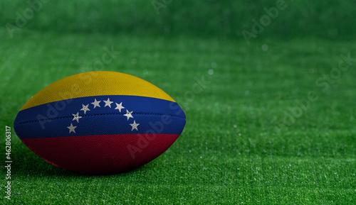 American football ball  with Venezuela flag on green grass background  close up