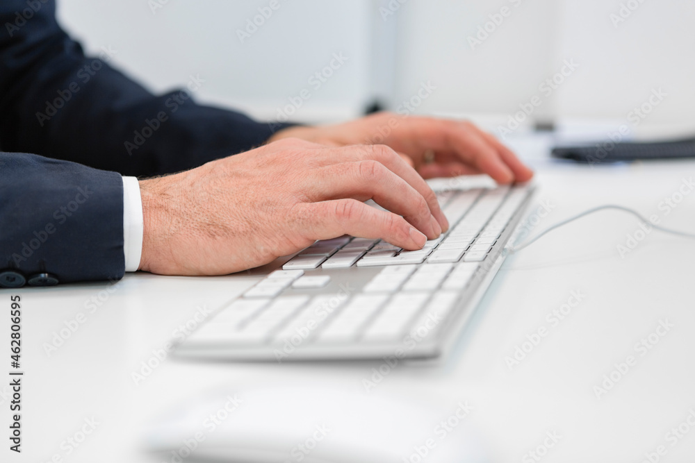 Close-up of businessman using computer keyboard at desk in office Close-up of businessman using computer keyboard at desk in office