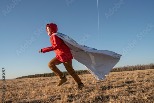Boy dressed up as superhero running in steppe landscape photo
