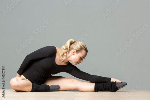 Blond woman doing stretching exercises on the floor photo