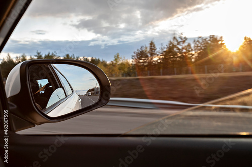 Voronezh, Voronezh Oblast, Russia, Shiny side-view mirror with sun setting in background photo