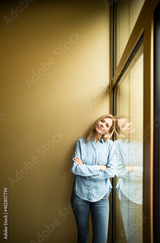 Businesswoman standing on a window, looking on camera, ams crossed photo
