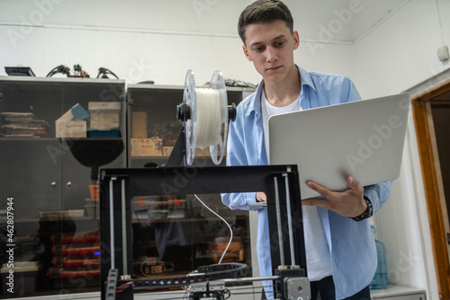 Student setting up 3D printer, using laptop photo