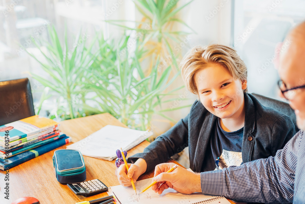 Portrait of smiling boy with father doing homework at desk Portrait of smiling boy with father doing homework at desk