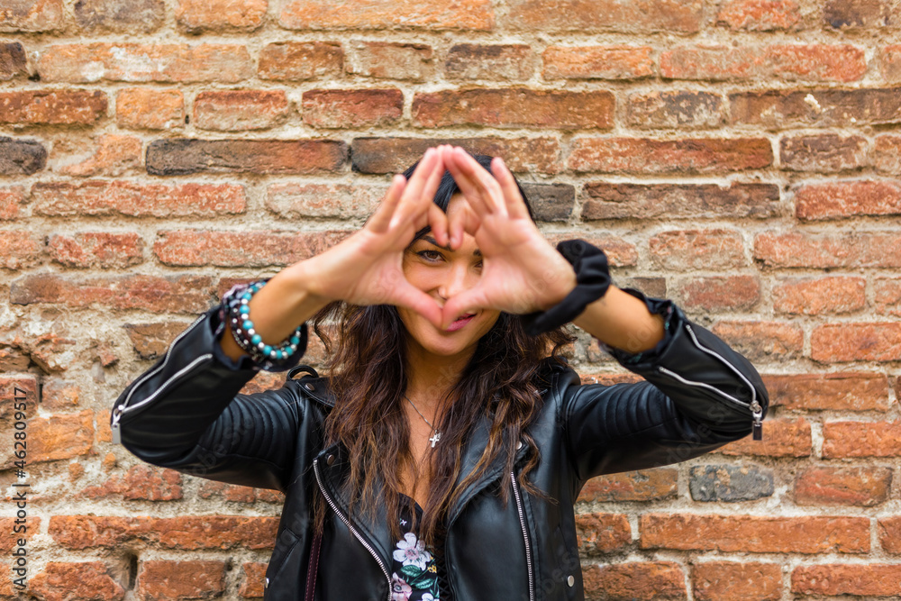 Portrait of young making heart shape with hands and fingers, brick wall Portrait of young making heart shape with hands and fingers, brick wall