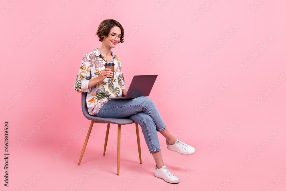 Full length body size photo woman working on laptop drikning coffee isolated pastel pink color background - obrazy, fototapety, plakaty 