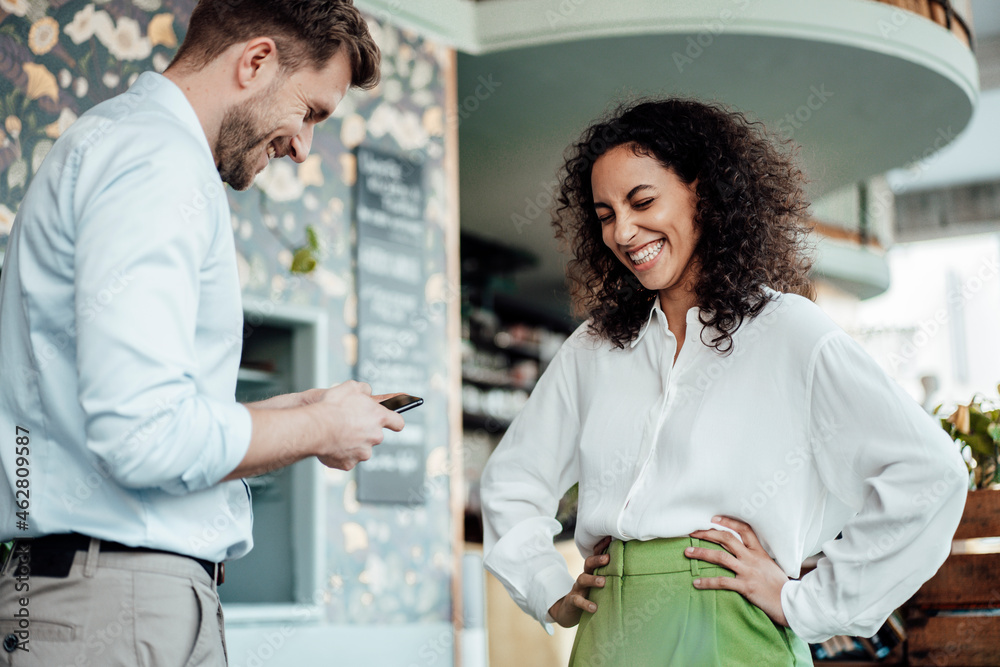 Businessman using mobile phone while standing by colleague at cafe Businessman using mobile phone while standing by colleague at cafe