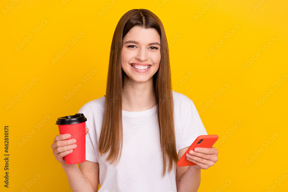Photo of young happy positive woman smile hold phone takeout coffee smile isolated on shine yellow color background - obrazy, fototapety, plakaty 