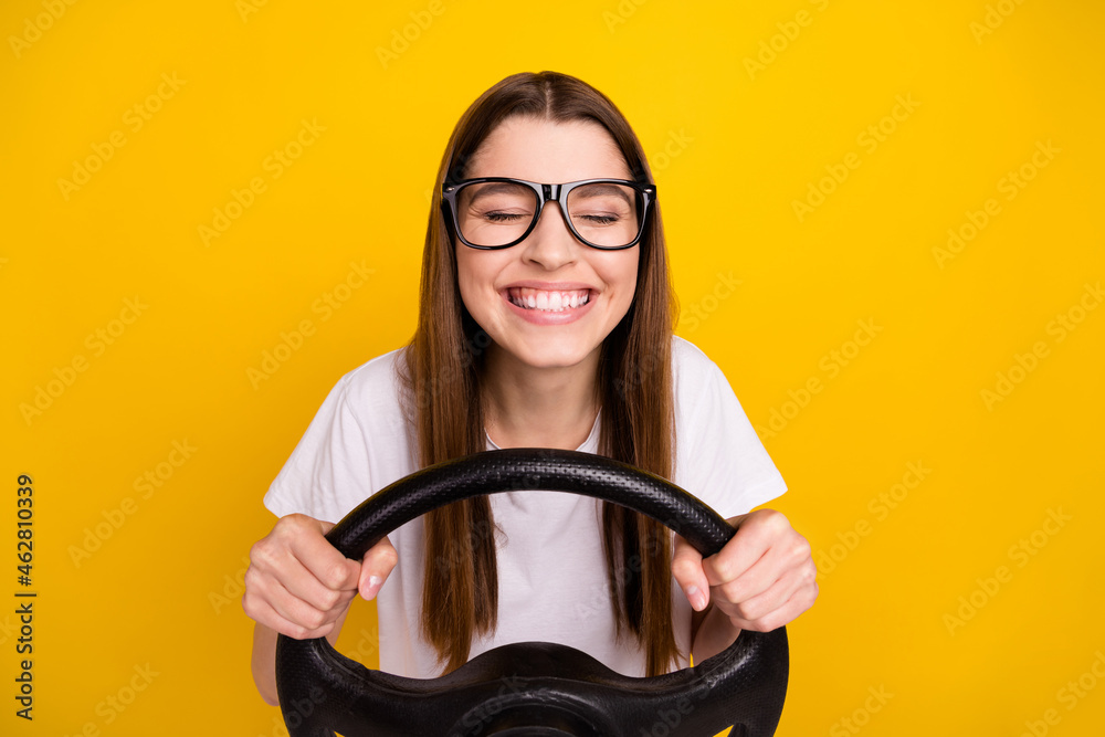 Photo of cheerful young positive joyful woman hold hands steering wheel isolated on yellow color background Photo of cheerful young positive joyful woman hold hands steering wheel isolated on yellow color background
